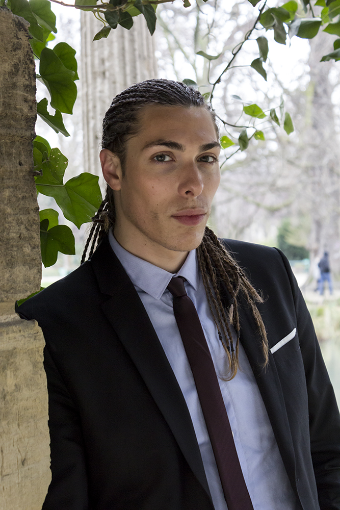 Alex Veach (Alexander Veach) Paris alt frame, navy suit against stone column.